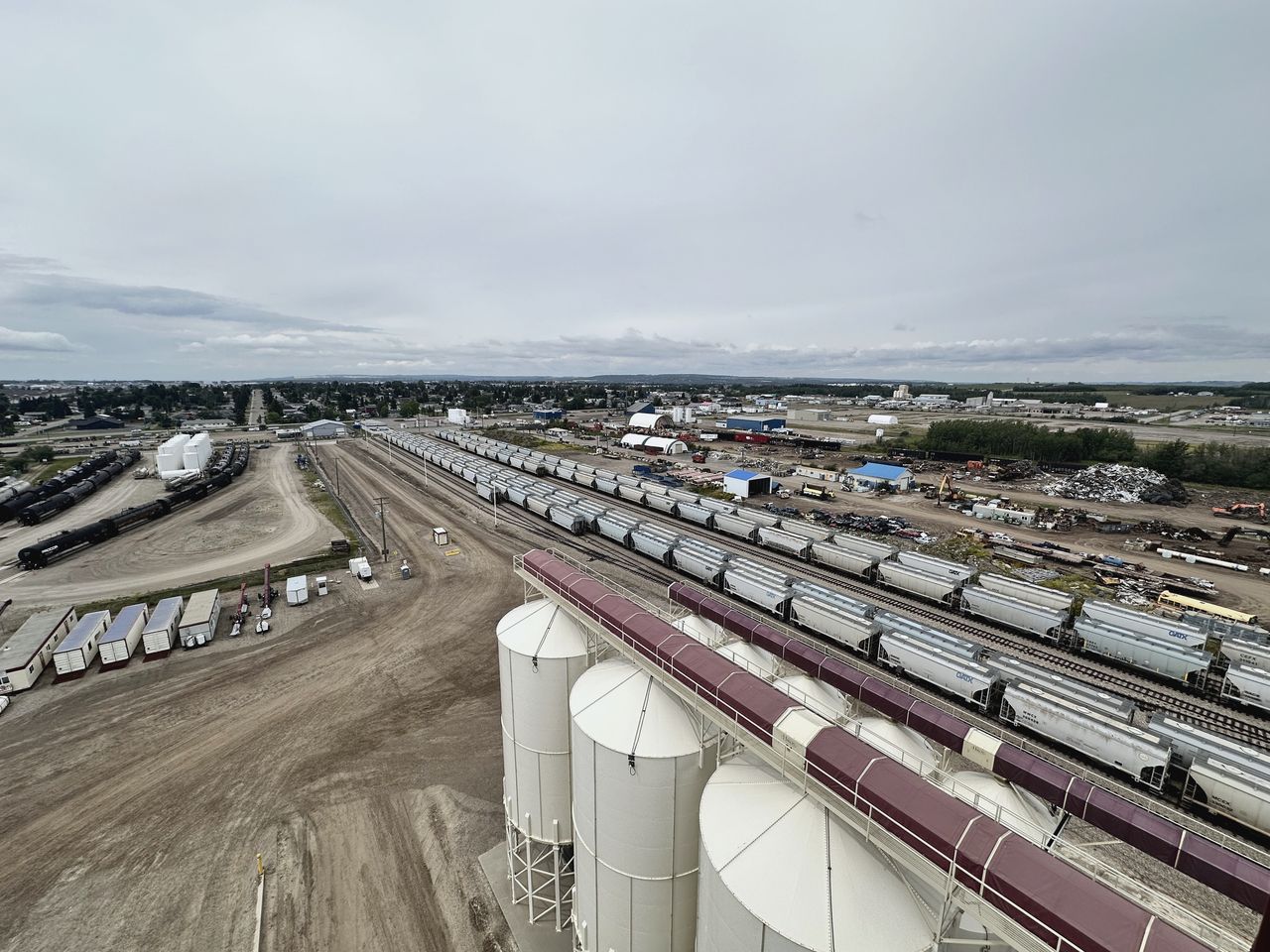 Elevated aerial view of a rail yard with strings of hopper cars and storage silos