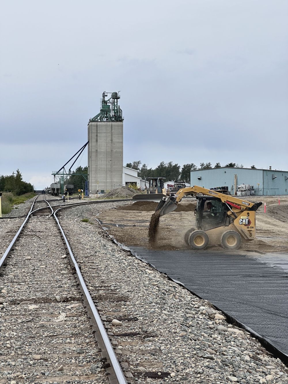 Concrete grain elevator with loader working beside the rail spur