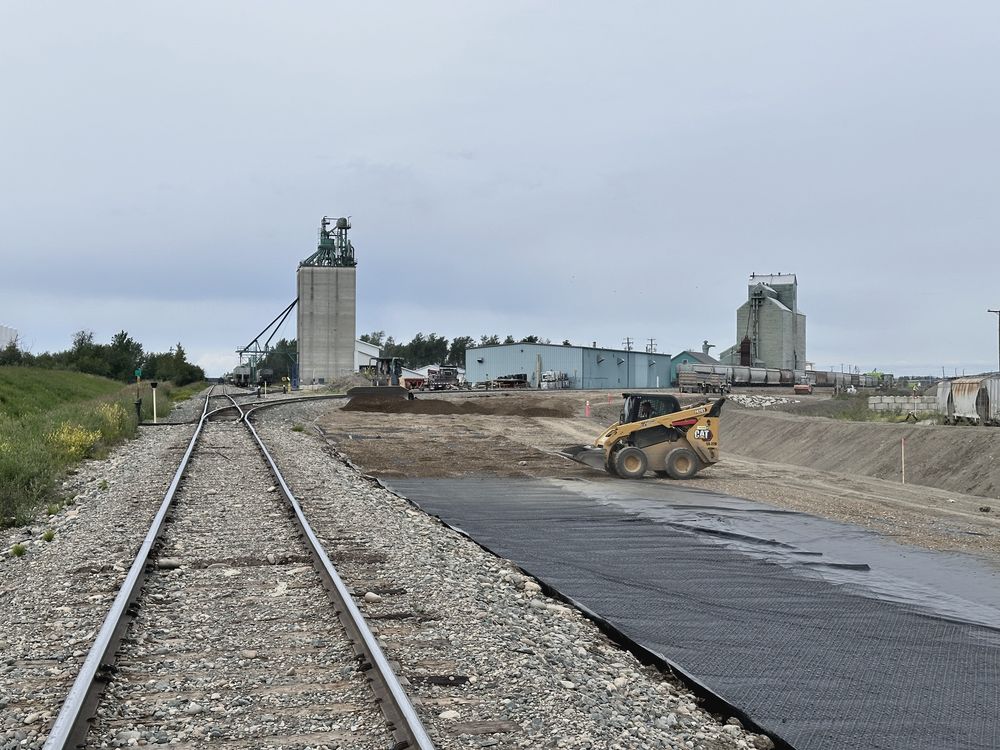Freshly graded pad with geotextile beside a new rail line and excavator