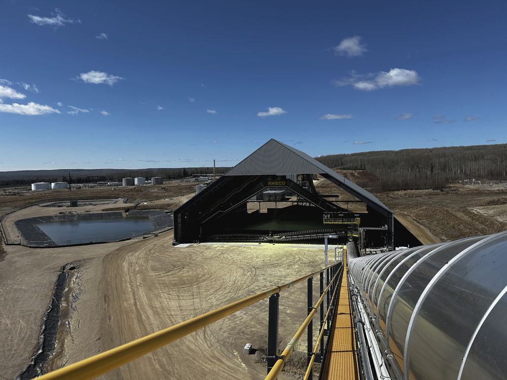 Panorama of a rail-served energy terminal with overhead conveyor gallery